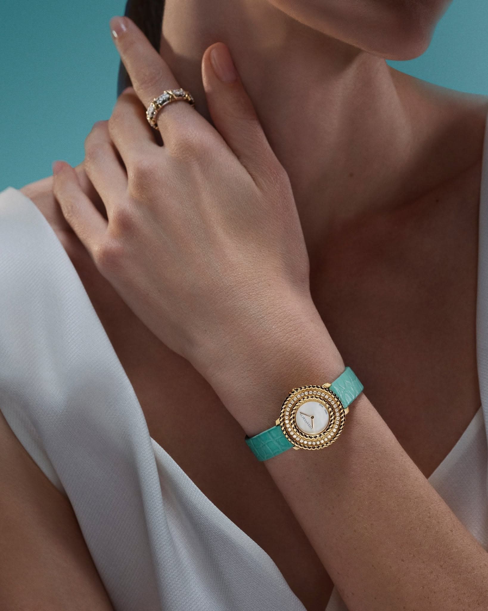 Tiffany & Co. rope-motif gold watch on a turquoise strap, worn with a diamond ring