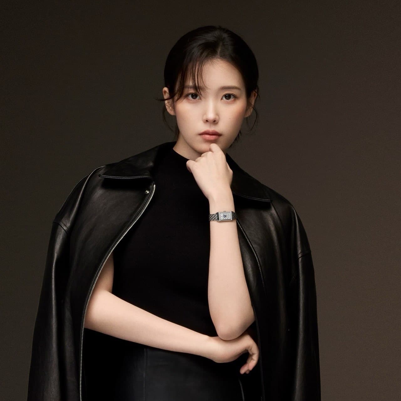 Jaeger-LeCoultre ambassador IU in a black leather coat, wearing a slim rectangular steel watch